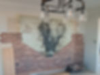 Exposed red brick accent wall in an interior room featuring an arched niche and decorative painted, animal art.