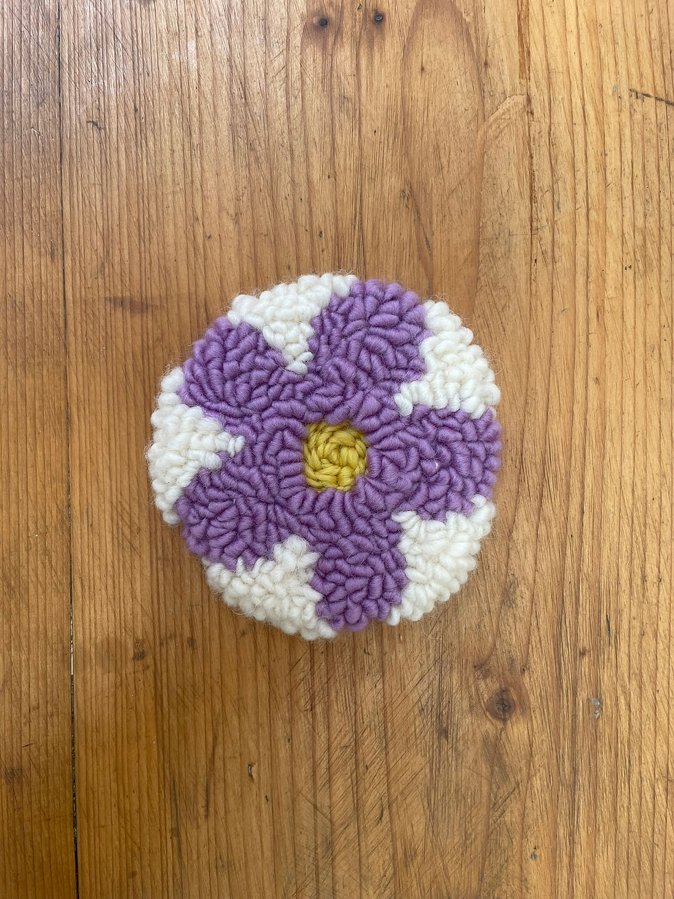 Handmade wool coaster with mauve retro flower and 60s-inspired design.