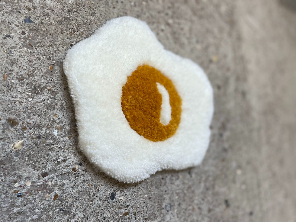 Thumbnail: Tufted wool fried egg rug design with yellow yolk and white edge, displayed on a felt backing.