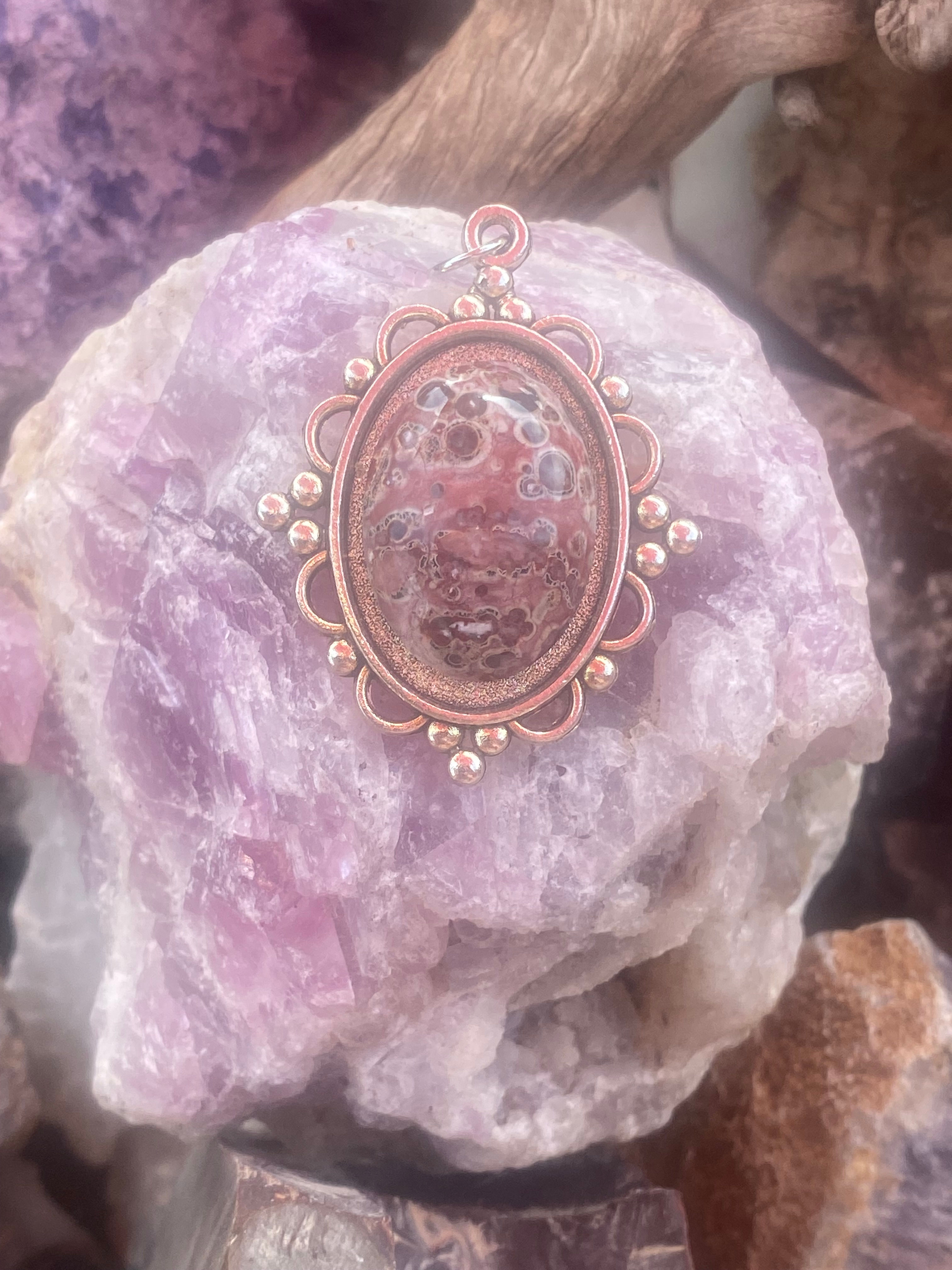 Leopard skin jasper pendant featuring unique patterns, displayed on a rough crystal background.