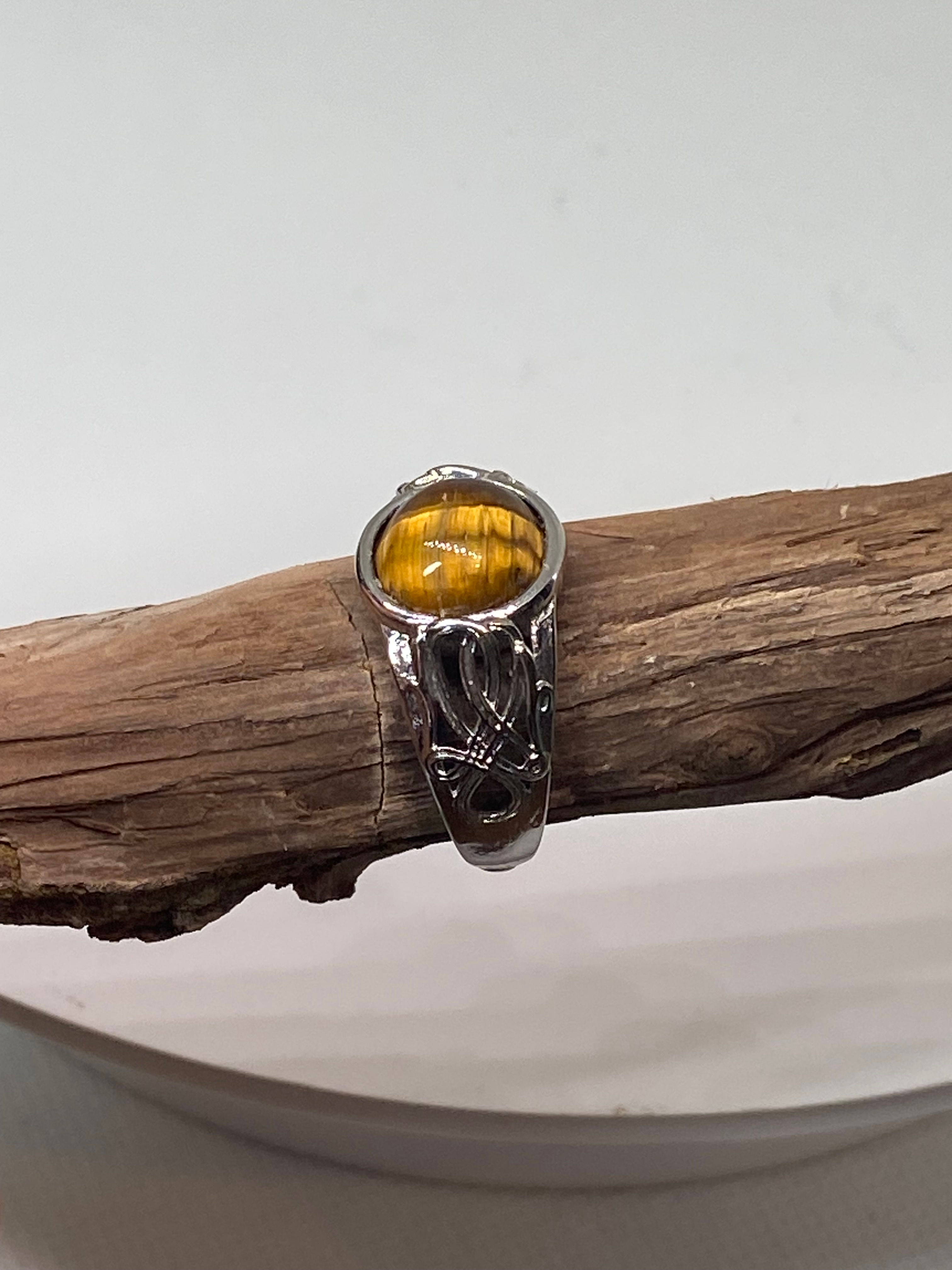Tiger's Eye ring with a polished golden-brown gemstone, set in a silver-plated band with intricate detailing.