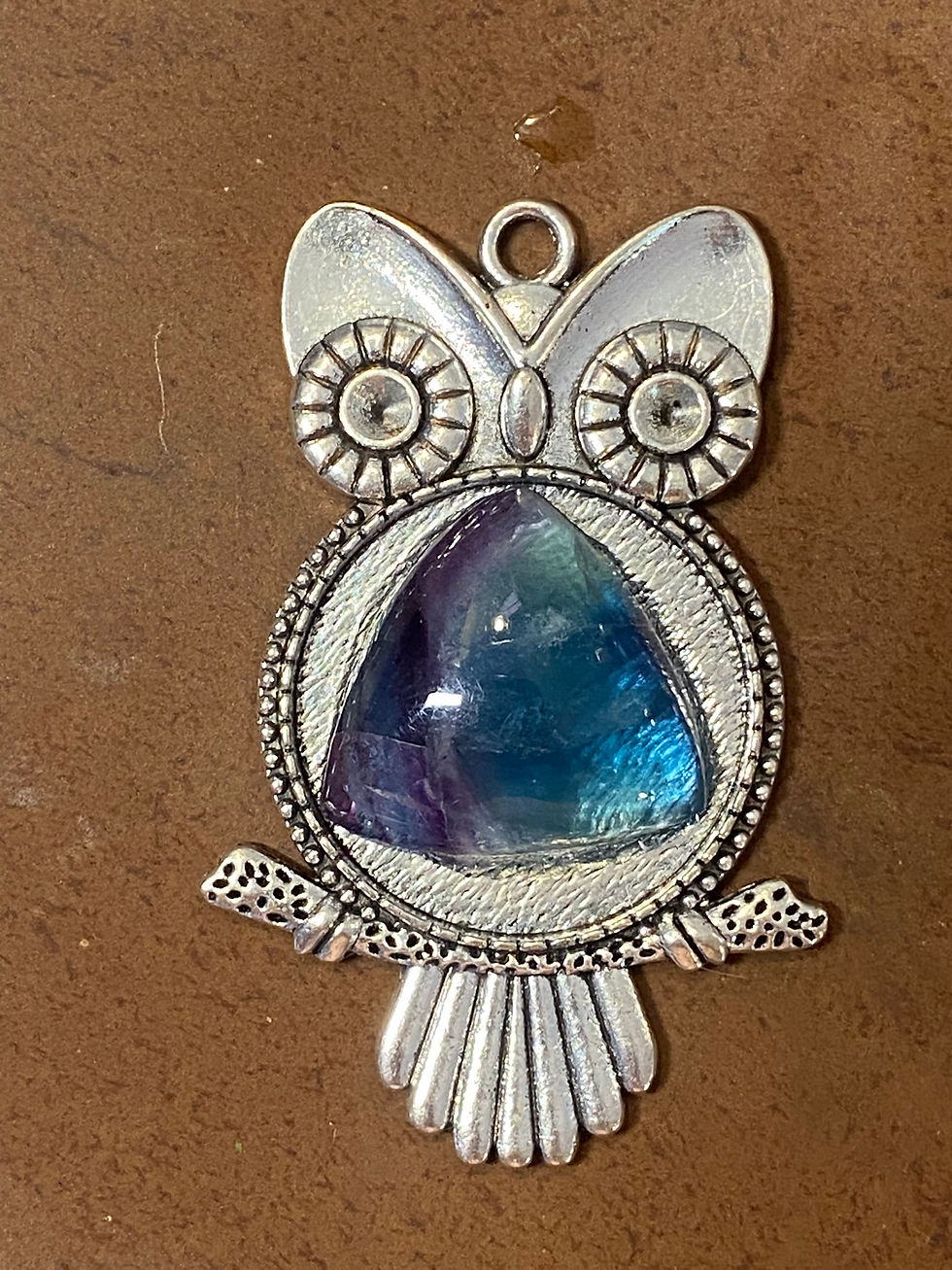 Owl-shaped silver pendant with a triangular fluorite cabochon in the center, intricate detailing around the edges.