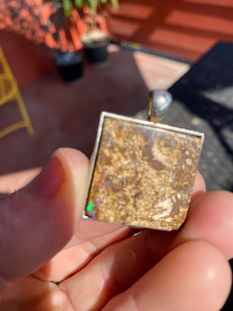Thumbnail: Close-up of square boulder opal pendant resting on purple and pink minerals.