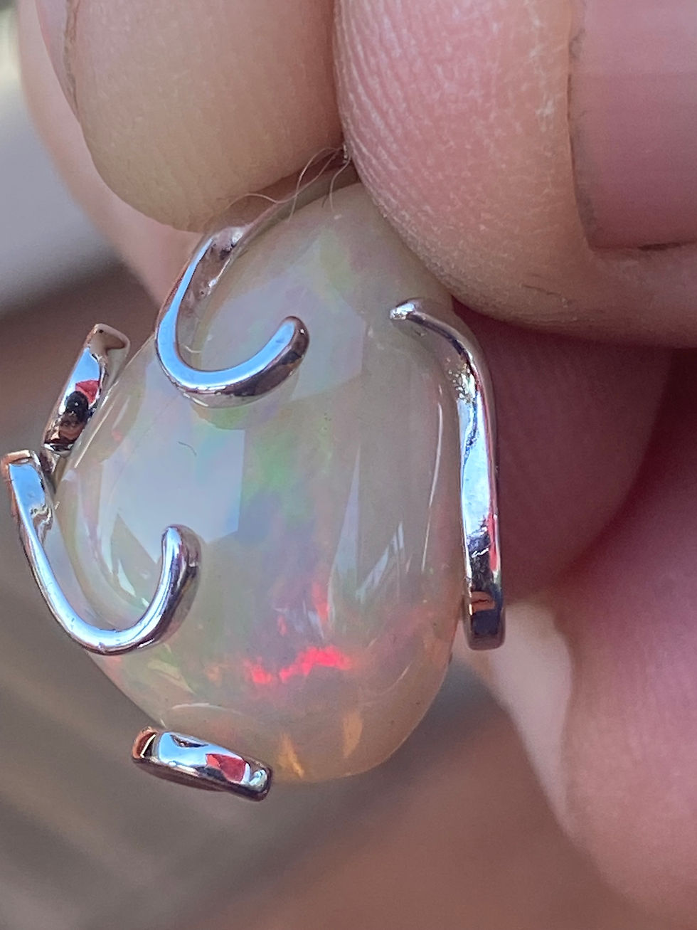 Thumbnail: Detailed side view of the opal pendant, highlighting the silver prongs gently curving around the opal. The opal's inner fire