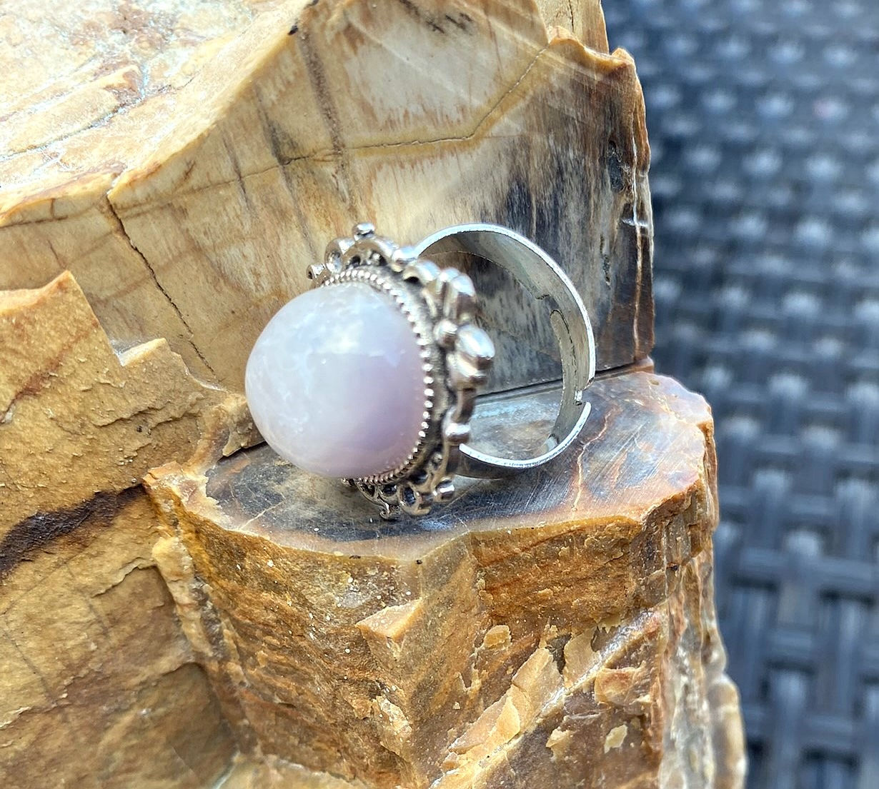 a silver-plated ring featuring a large amethyst quartz stone, with intricate floral detailing on the band.