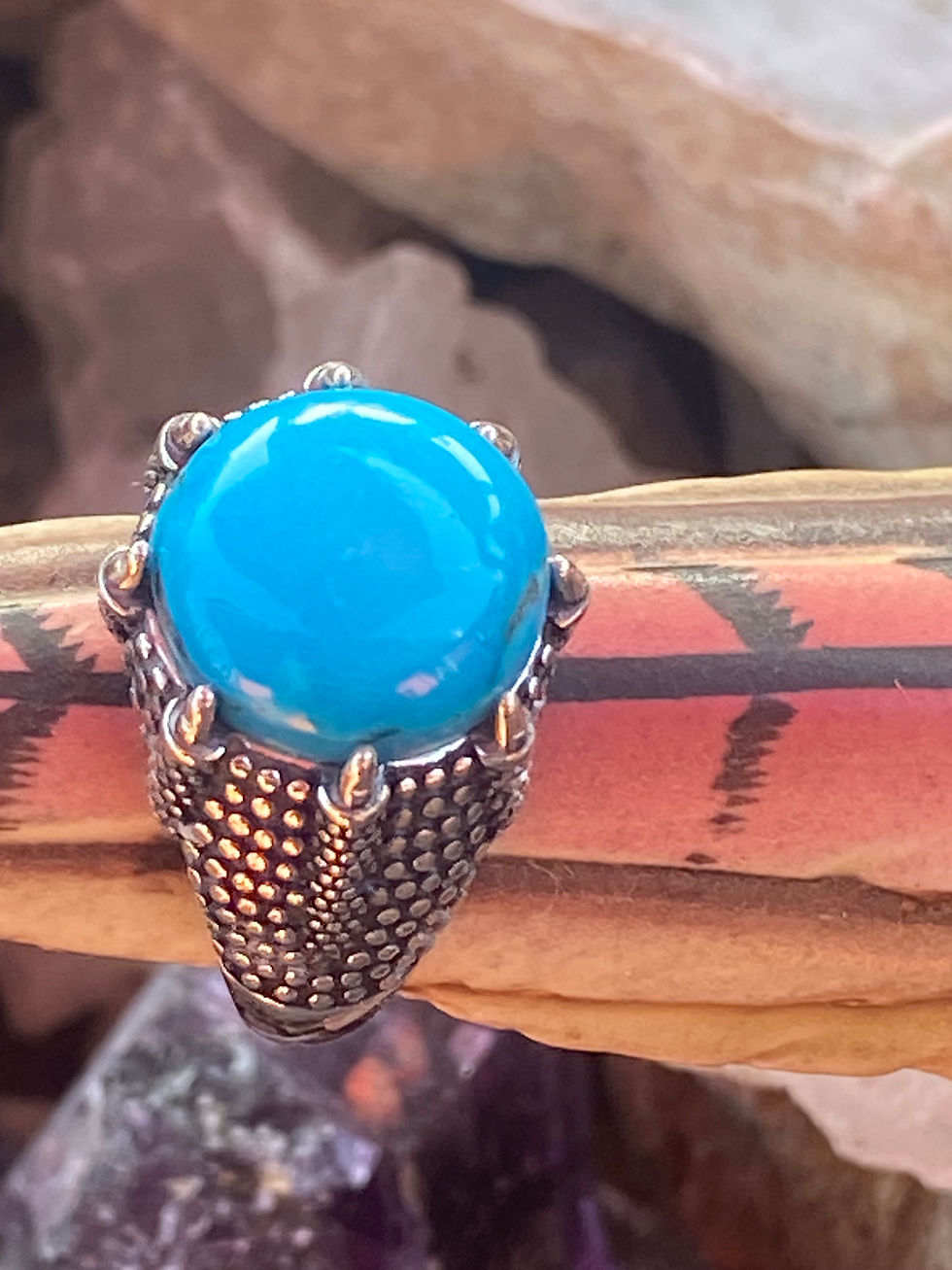 Close-up of a round Arizona turquoise ring with a bright blue cabochon, set in a textured silver band.