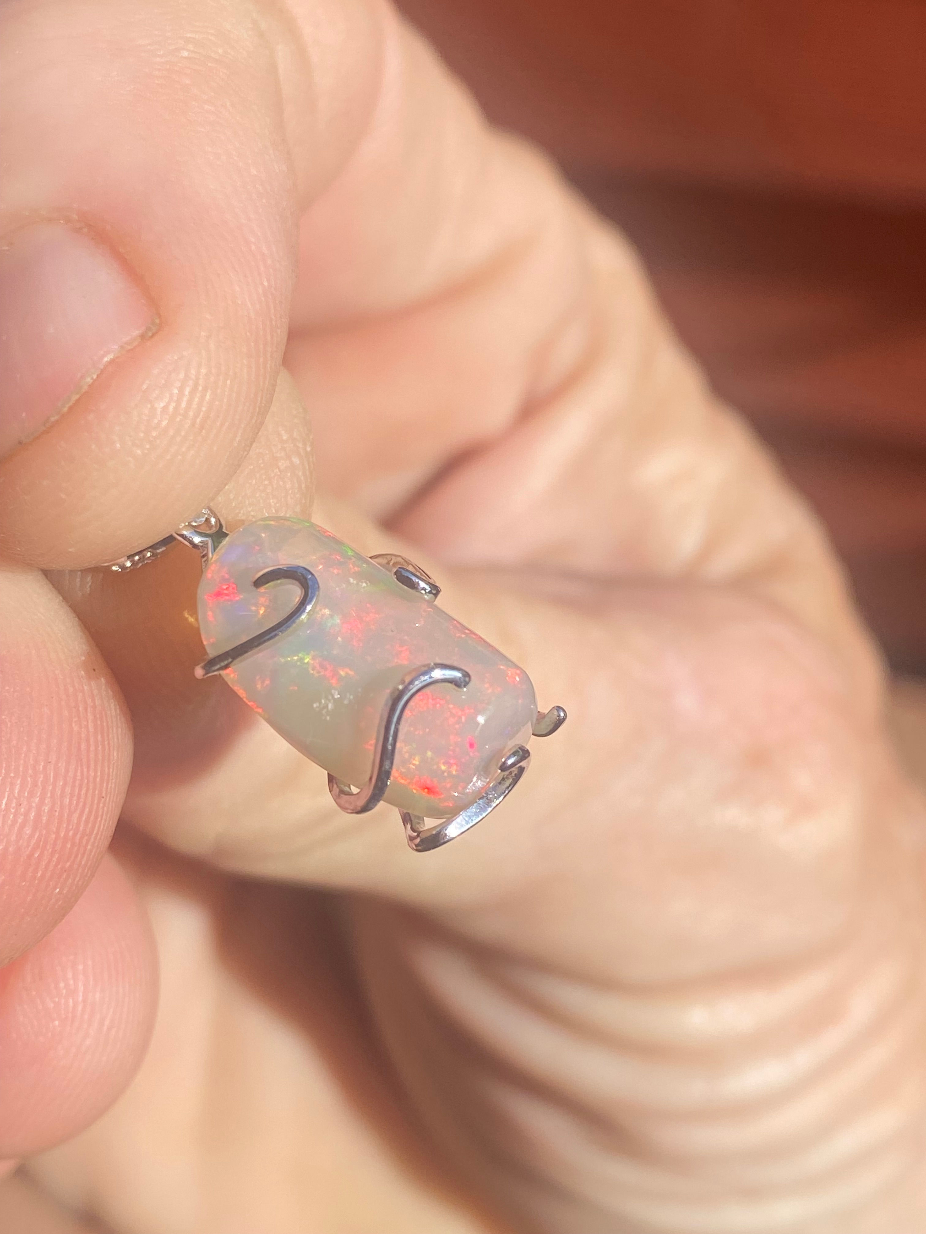 Close-up of Welo Opal pendant wrapped in silver, showcasing its vibrant play of colors.