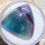 Thumbnail: Triangular fluorite cabochon showcasing shades of teal, purple, and clear, displayed on a white background.