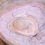Thumbnail: Polished Banded Agate gemstone with soft cream and white bands resting on a natural stone background.
