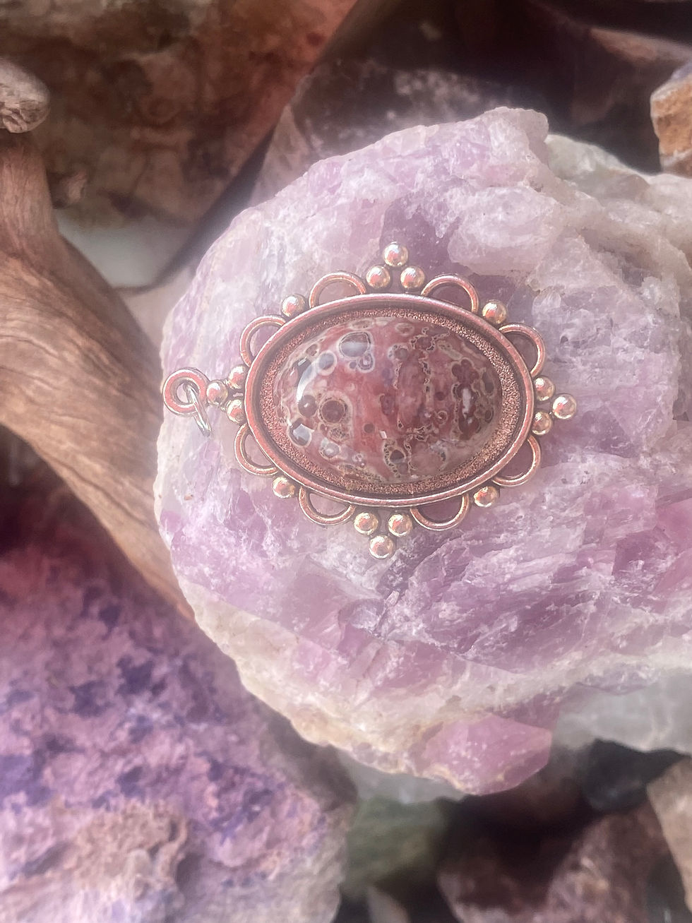 Leopard skin jasper pendant featuring unique patterns, displayed on a rough crystal background.