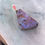 Thumbnail: Close-up view of a triangular boulder opal pendant with vibrant purple, blue, and earthy brown swirls, set in a silver bail.