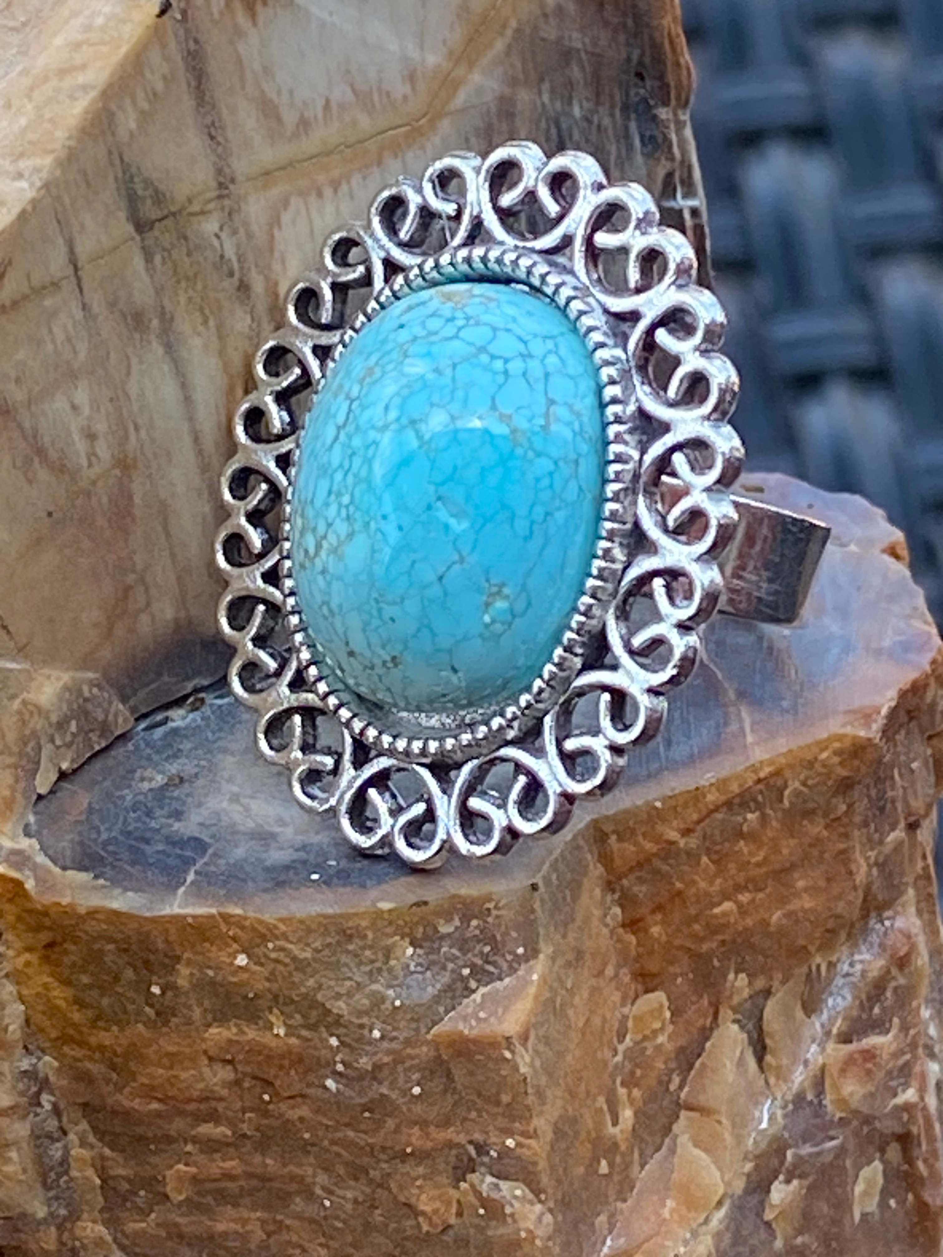 Side view of Oval-shaped Arizona turquoise ring set in an ornate silver-plated band with intricate scrollwork.