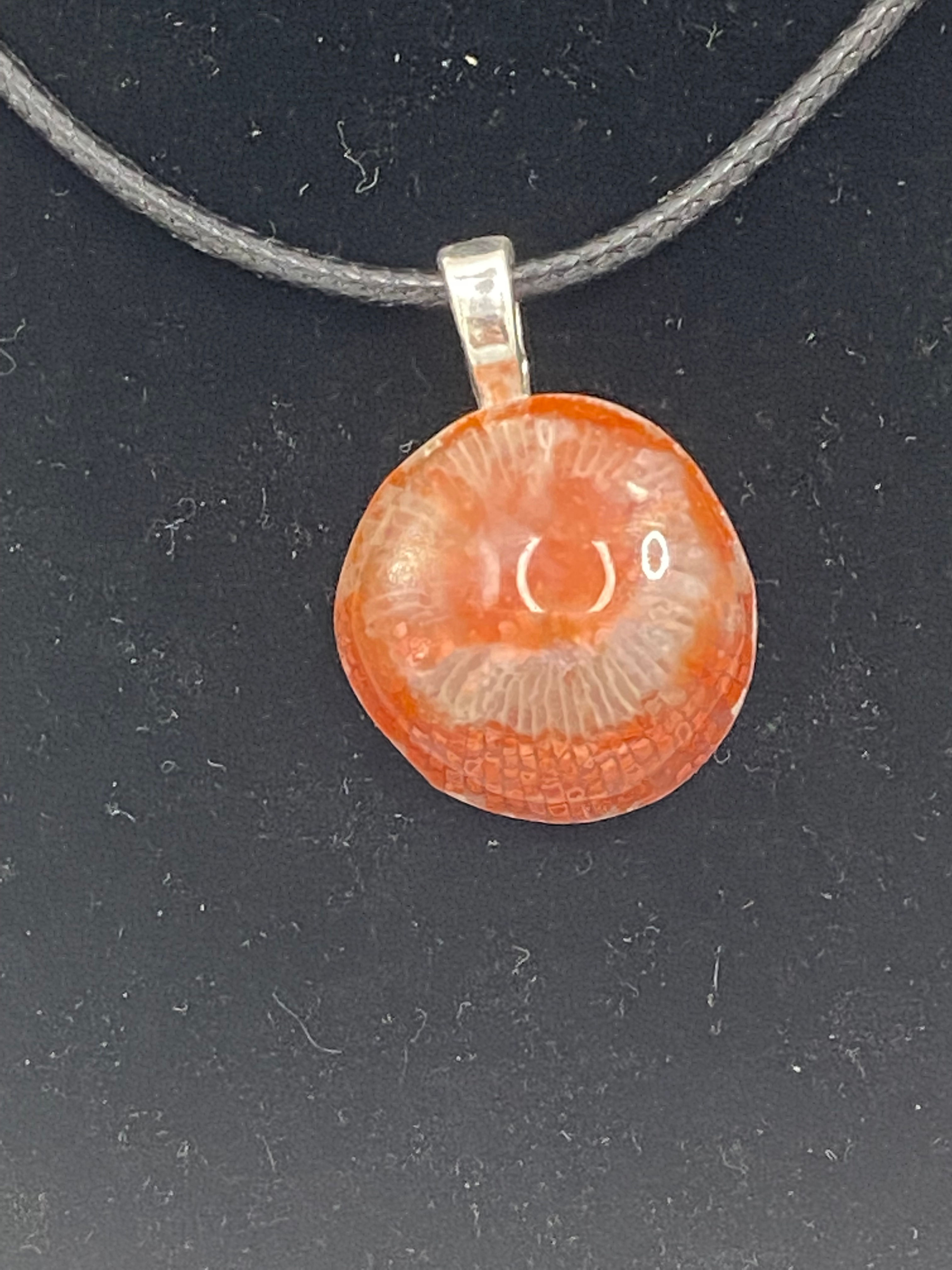 Close-up of Fossilized Red Coral pendant showcasing its intricate patterns and natural beauty.