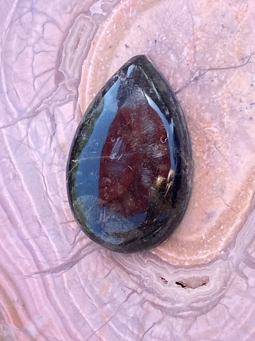 Close-up of Kambaba Jasper pendant showcasing intricate green orbs and earthy black tones.