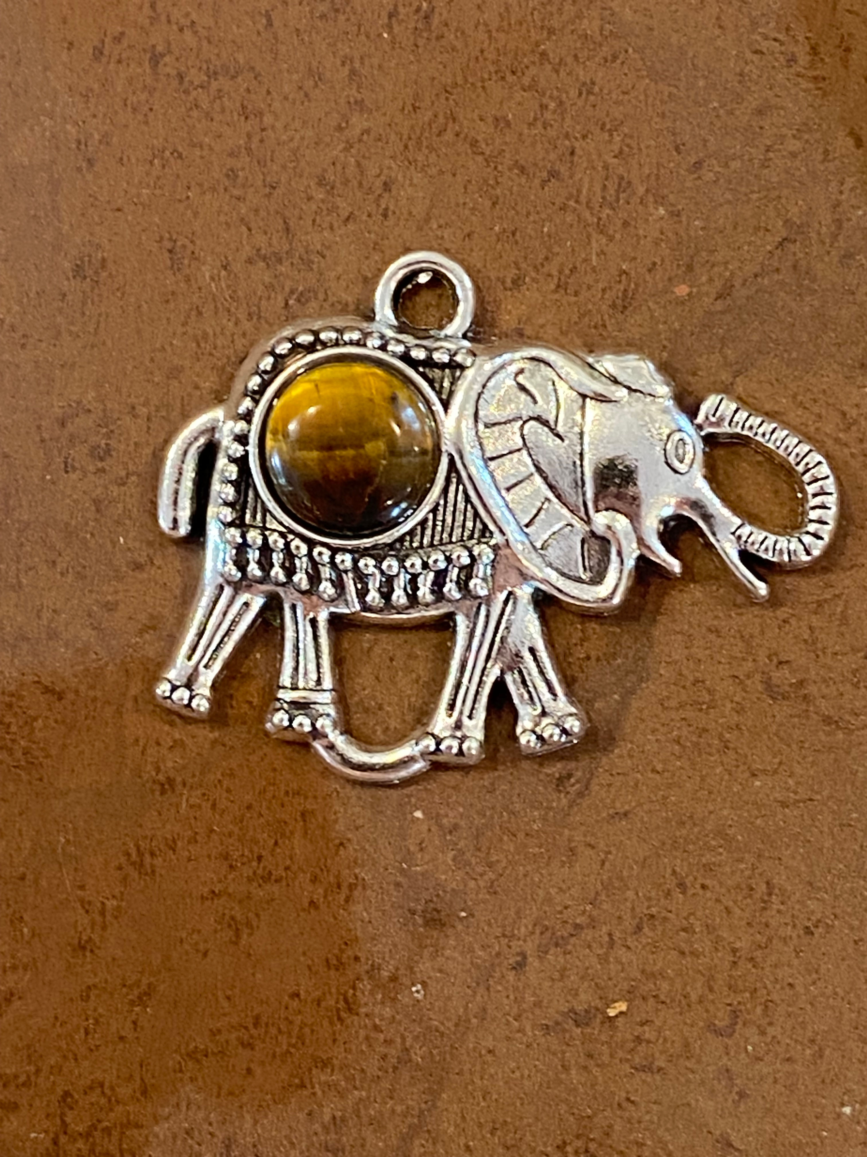 Silver elephant pendant featuring a tiger eye gemstone in its center.