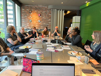A long table covered in papers, drinks, and laptops as the team sits around and strategizes.