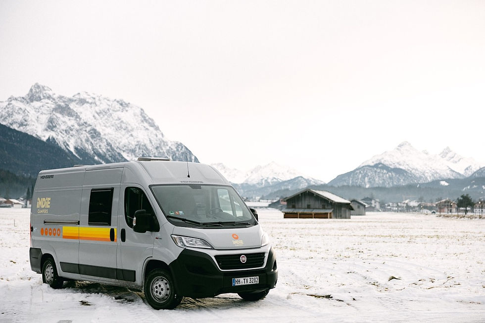 indiecampers rental campervan parked in a snowy field in the mountains