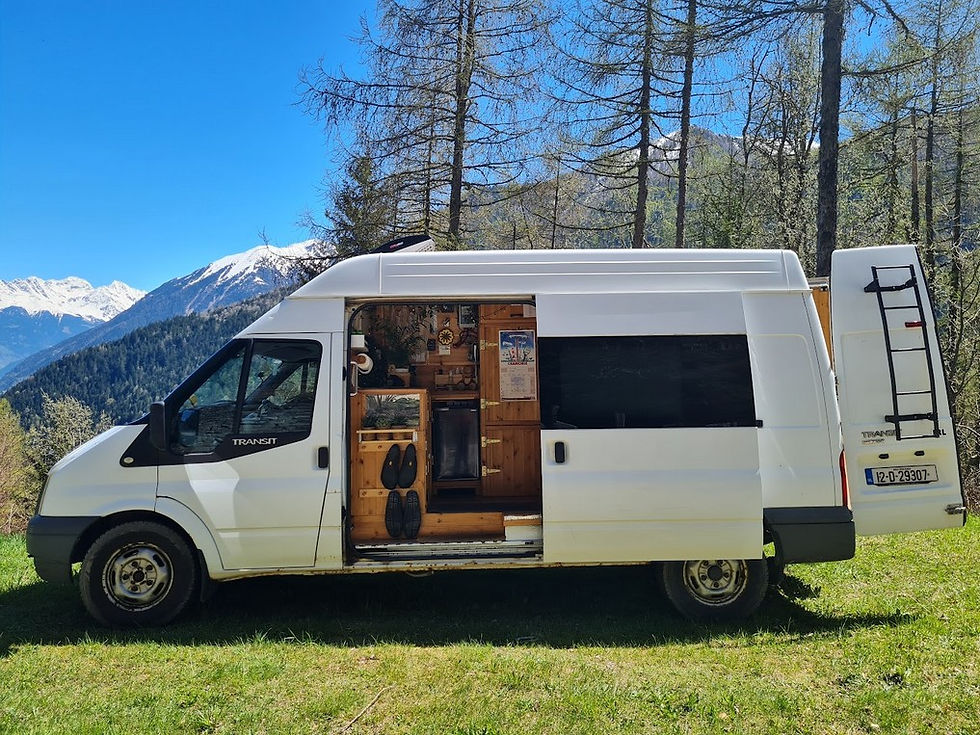 A converted campervan parked in a field in the Alps