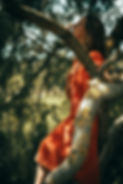 Frau auf einem Baum zwischen Ästen; Hand auf dem Herzen