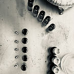 Photo of a collection of small dark coloured glass bottles taken from above upon a steel like surface.