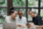 A group of three young women talking and looking at a phone together