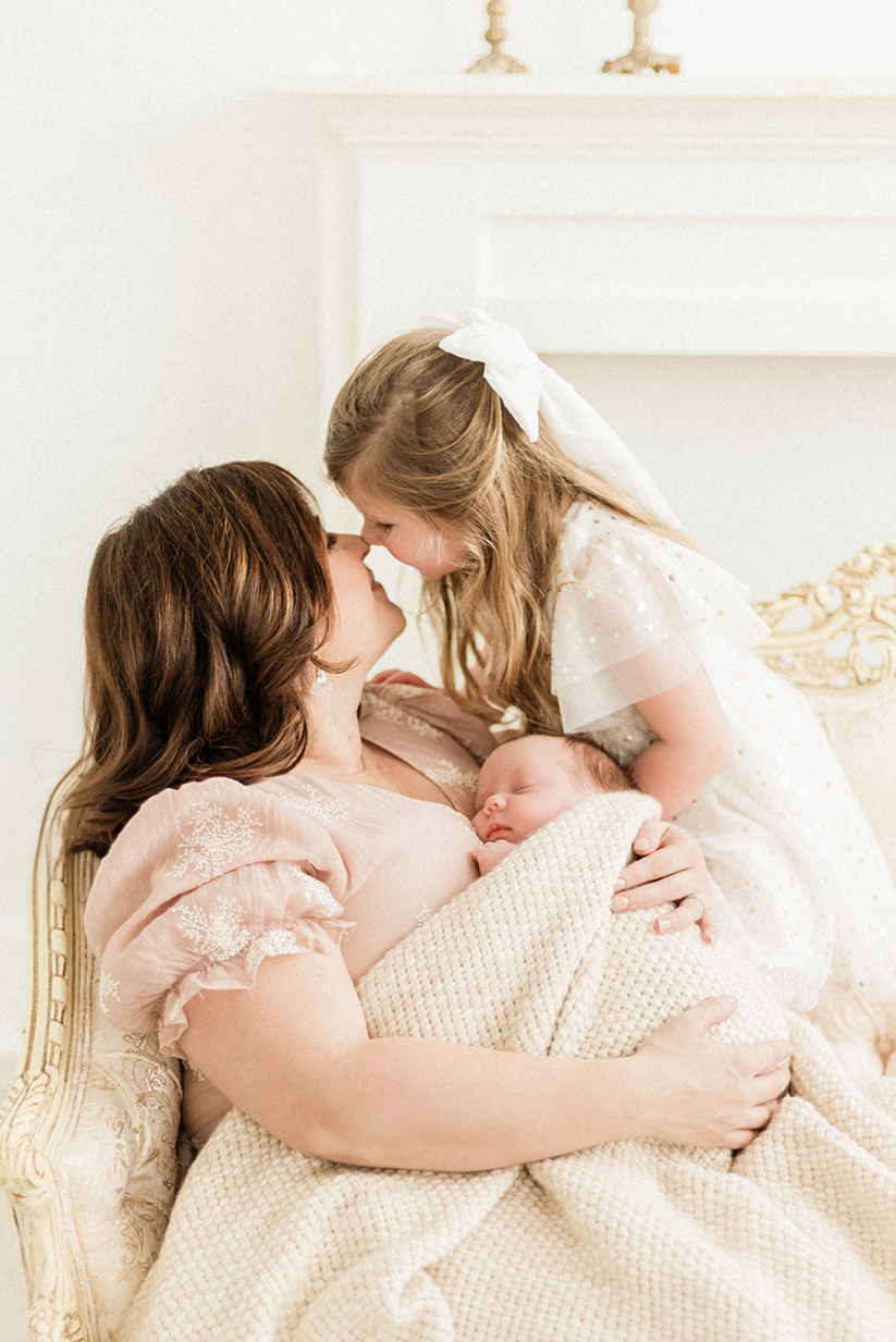 Mom, big sister and baby hugging