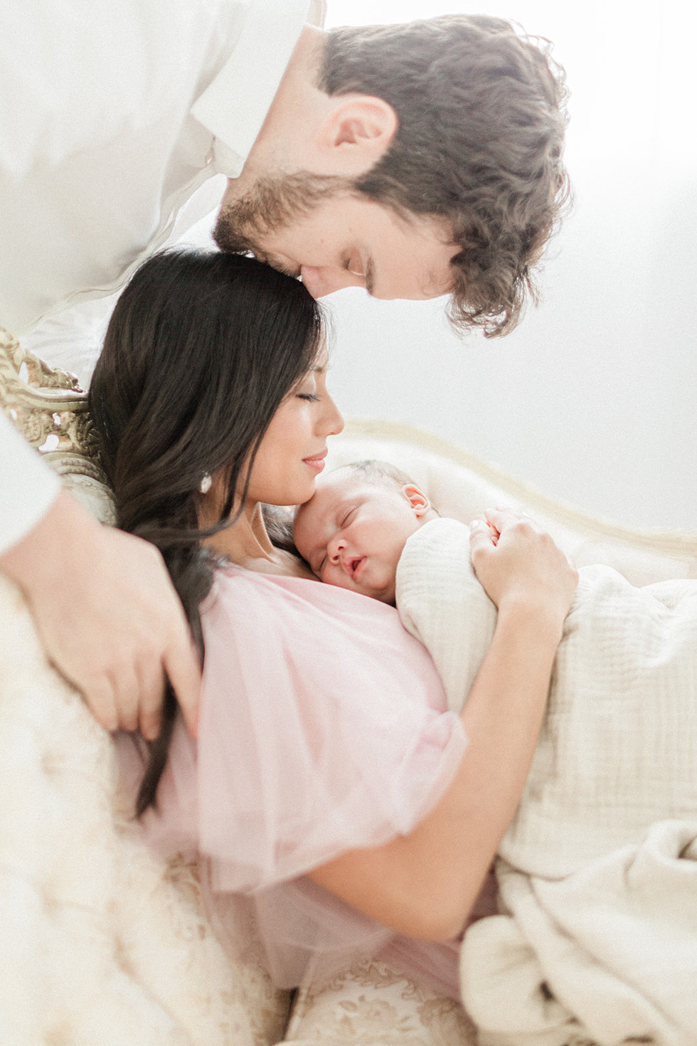 Dad kissing Mom's head while holding baby