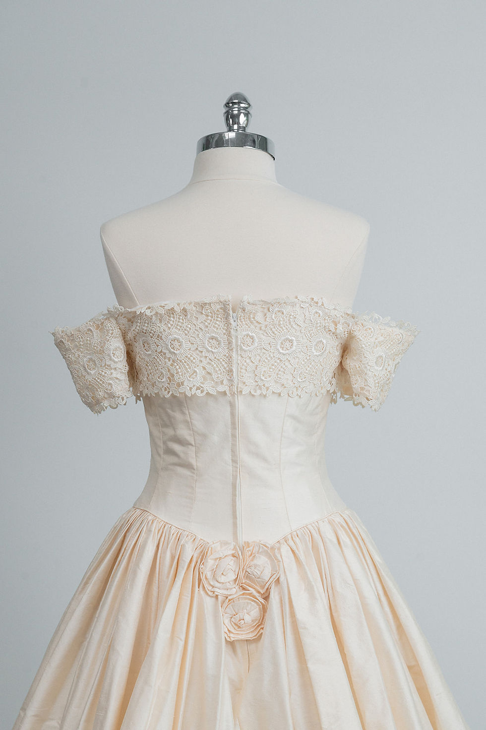 Thumbnail: Back bodice view of British vintage silk wedding dress with dropped waist on dress form in Atlanta bridal shop