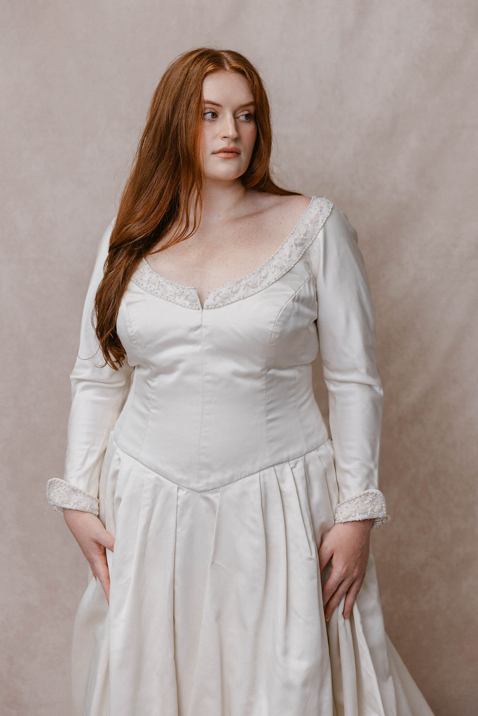 Thumbnail: Red-haired model wearing plus size couture vintage wedding dress against beige backdrop