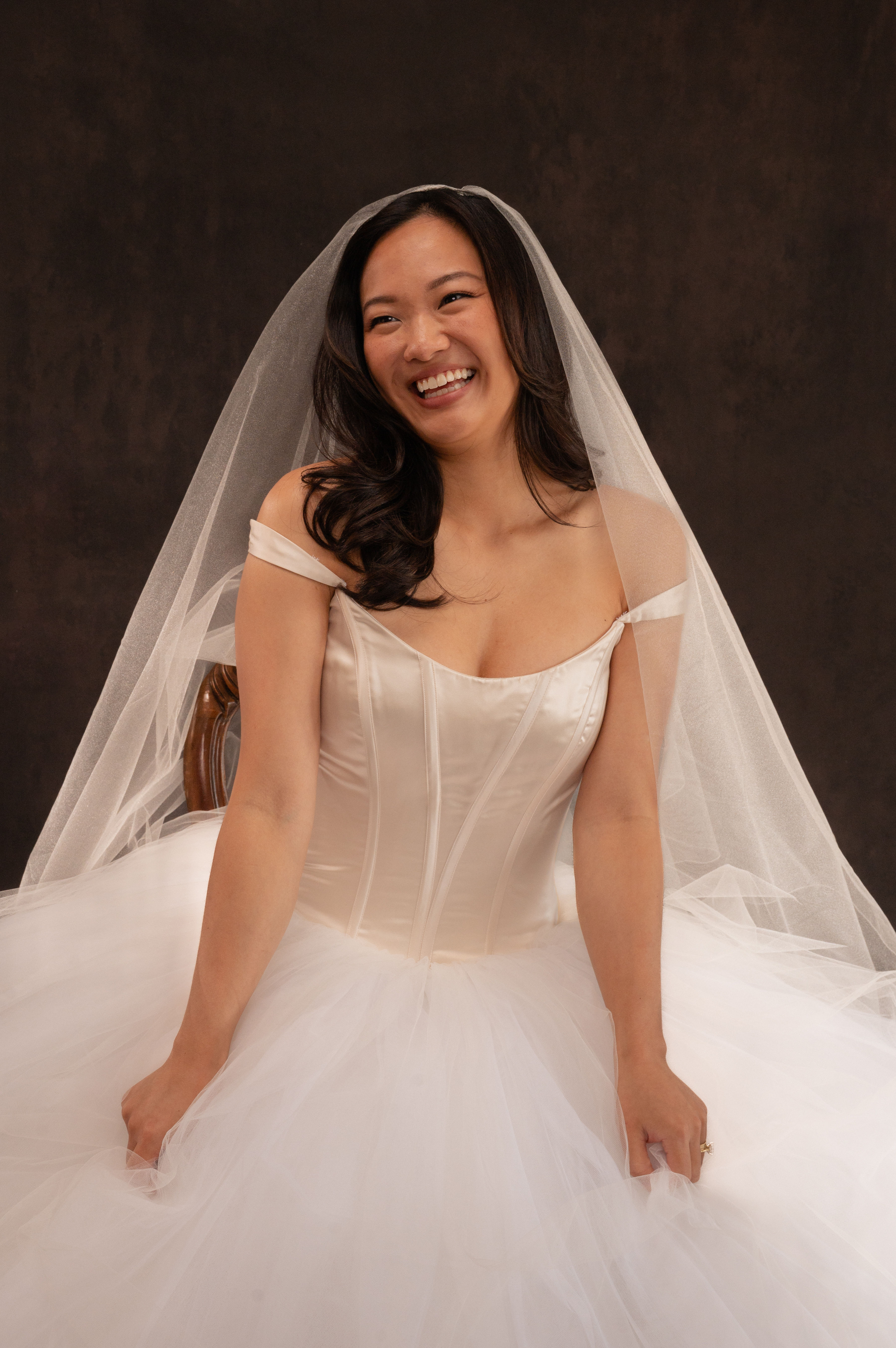 Model sitting down and smiling in vintage Vera Wang wedding dress with tulle skirt