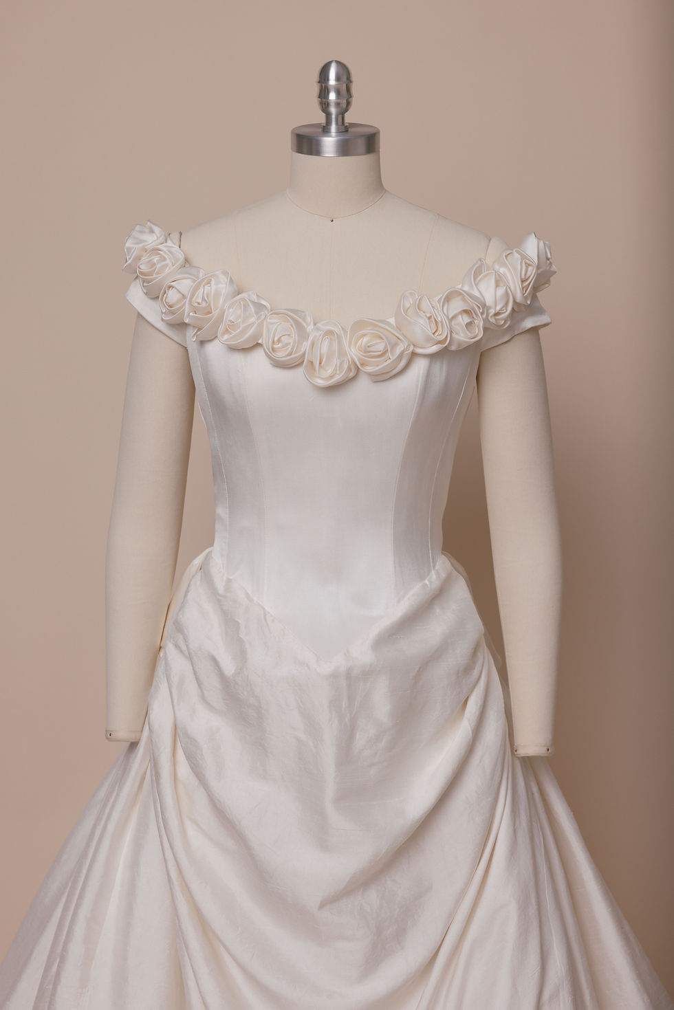 Catherine Rayner wedding dress with rosette neckline on mannequin against beige backdrop at Atlanta bridal shop