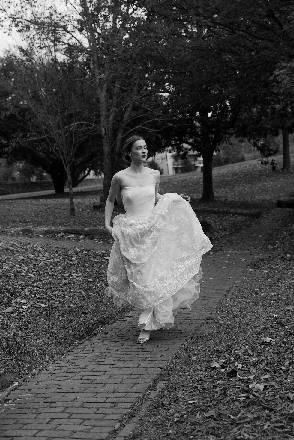 Thumbnail: Black and white photo of bride running towards the camera in vintage lace wedding dress