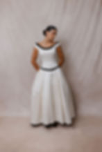 Thumbnail: Model wearing 1990 black and white Vera Wang wedding dress against beige backdrop at Atlanta bridal shop
