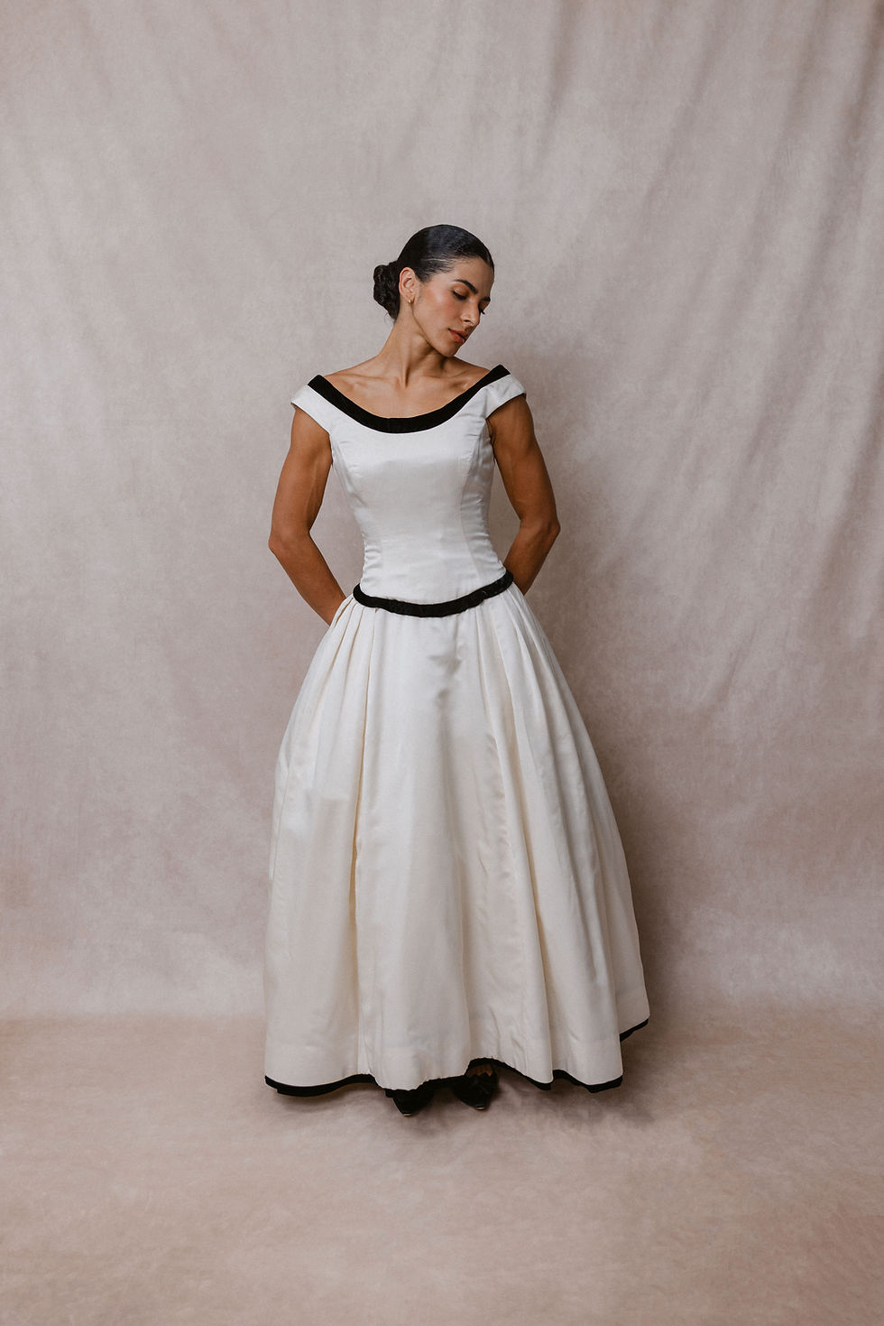 Thumbnail: Model wearing 1990 black and white Vera Wang wedding dress against beige backdrop at Atlanta bridal shop