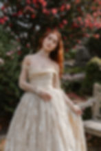 Red haired model swaying in a garden in a gold French lace vintage wedding dress