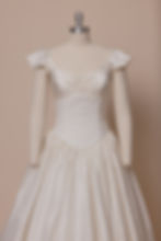 Vintage Victorian inspired silk wedding dress with cap sleeves and ruched neckline against beige backdrop