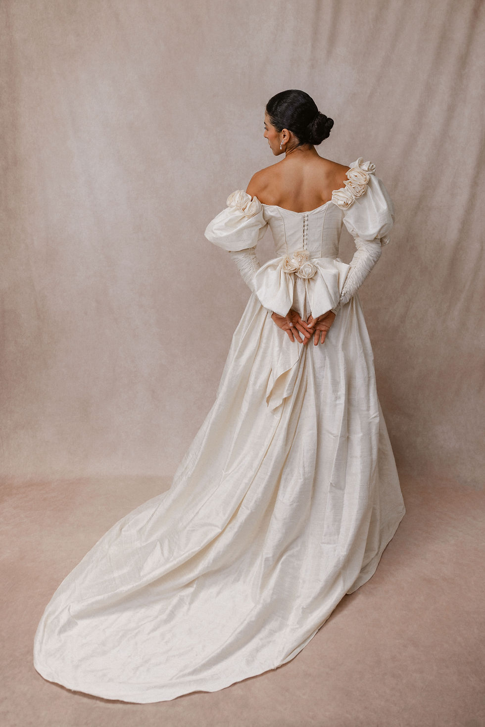 Thumbnail: Bride wearing Anneliese Sharp vintage wedding dress against beige backdrop in Atlanta bridal shop