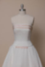 Vintage Carolina Herrera wedding dress with pink accents on dress form against ivory backdrop