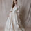 Thumbnail: Red haired model wearing Renaissance inspired vintage wedding dress with off shoulder sleeves against beige backdrop
