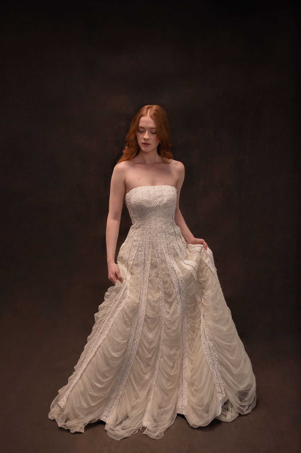 Model wearing vintage crochet lace wedding dress against brown backdrop in Atlanta bridal shop