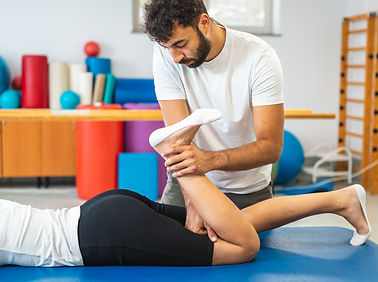 Male physiotherapist giving exercise therapy for sciatica to a female patient in a supine