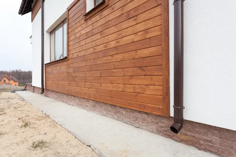 Home Siding - New brown copper gutter in house with white wall and wooden planks