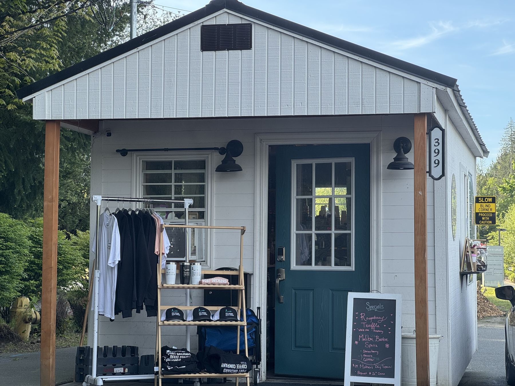 The coffee stand at 399 S Kitsap Blvd: white building, teal door, wood posts