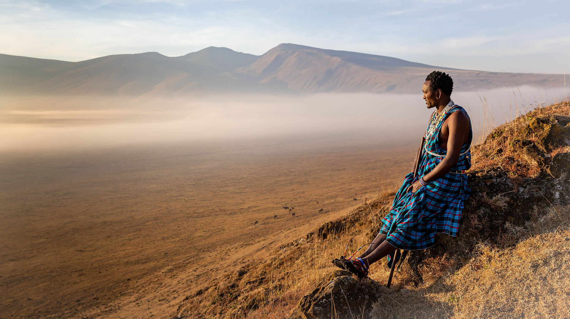 East African sitting on a hill looking over a valley