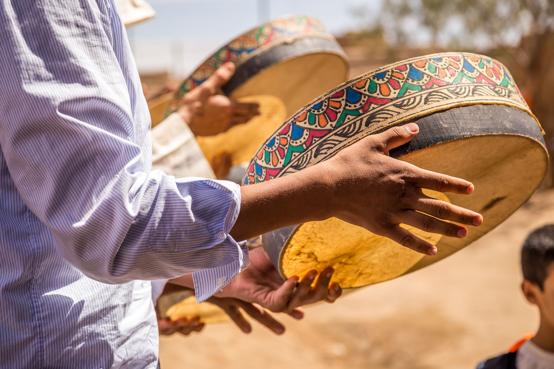 person in white shirt playing a colorful hand drum in Morocco