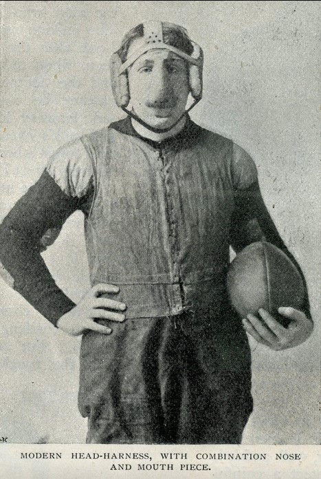 black and white photo of football player with a head harness and face mask over his nose while holding a football