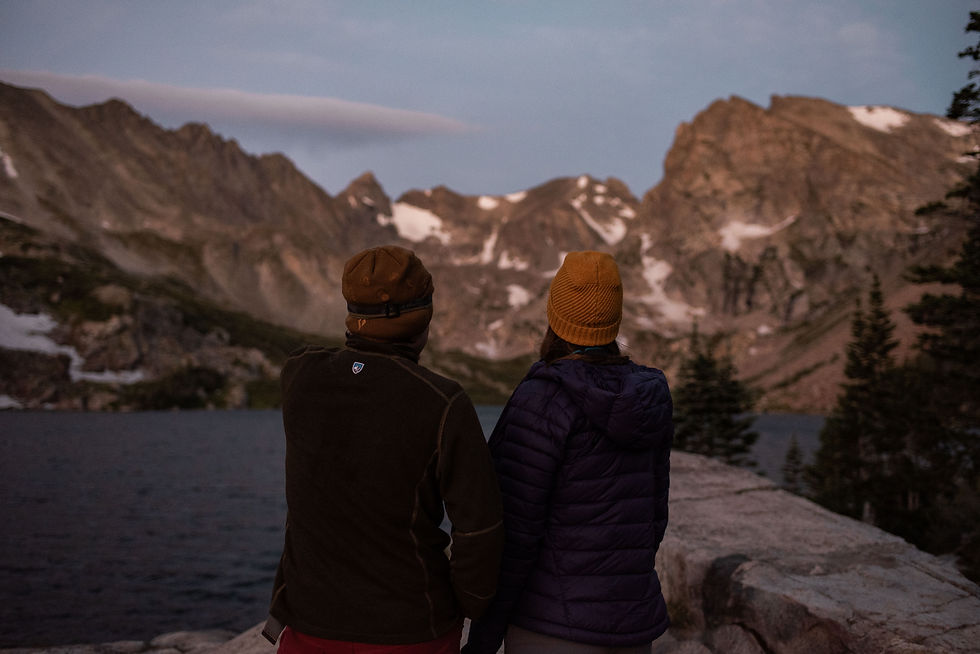 Man and woman watch the sunrise over Lake Isabelle in Colorado