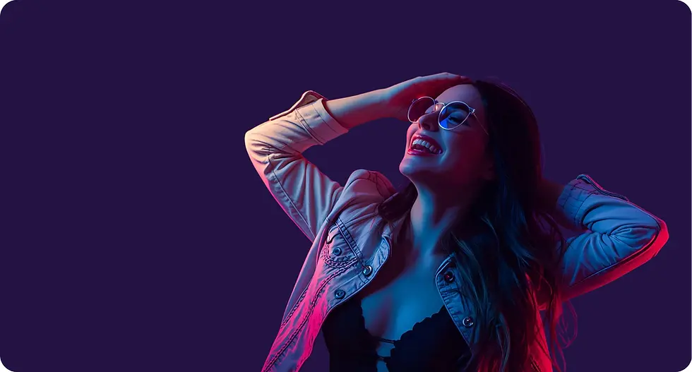 Smiling woman holding her hair with glasses on, looking to the side.