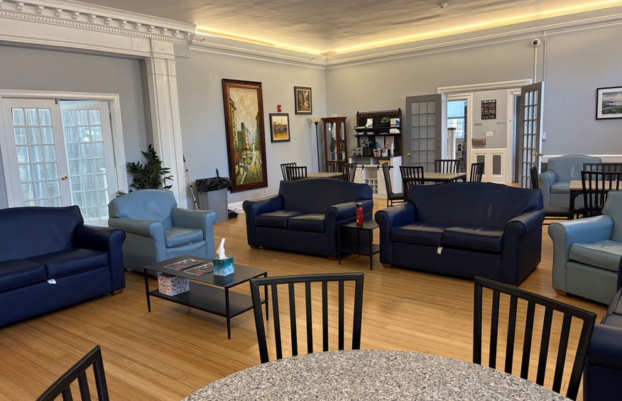 Community living room at Parents' Foundation Group Home featuring cozy seating areas, communal tables, and warm lighting to encourage resident interaction and relaxation.