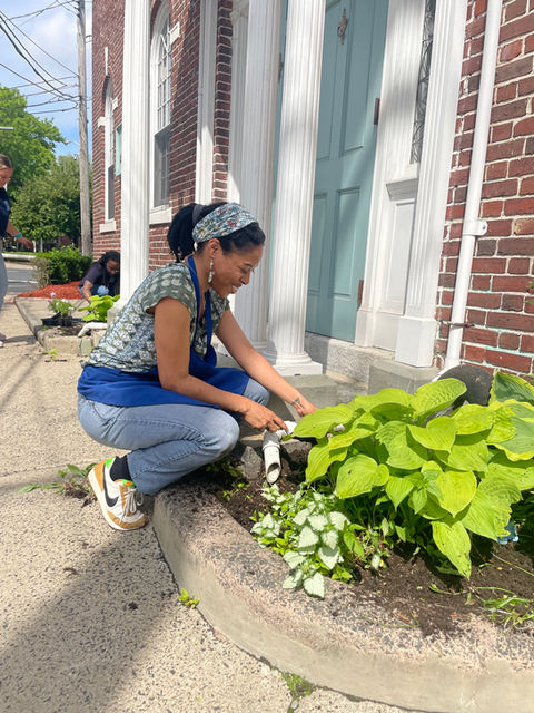 Staff member planting in the front garden, tending to the plants and flowers with care.